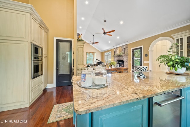 kitchen with appliances with stainless steel finishes, a fireplace, dark hardwood / wood-style floors, cream cabinets, and ceiling fan