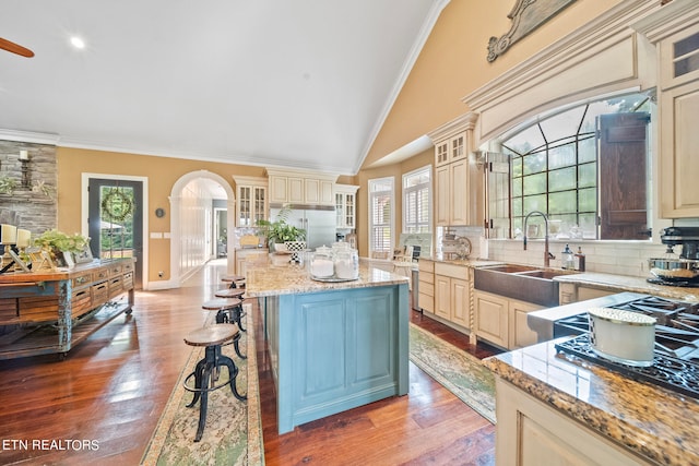 kitchen with sink, backsplash, light hardwood / wood-style floors, a kitchen island, and cream cabinets