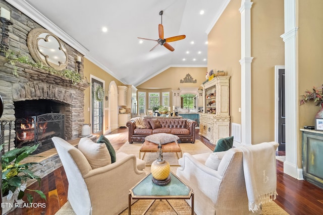 living room featuring a stone fireplace, crown molding, ceiling fan, and light hardwood / wood-style flooring