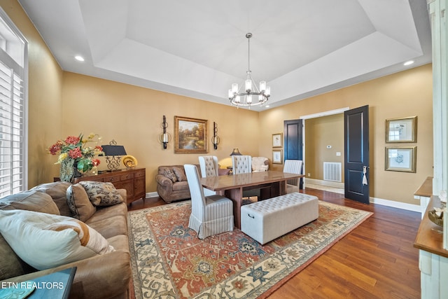 dining room with a chandelier, dark hardwood / wood-style floors, and a raised ceiling