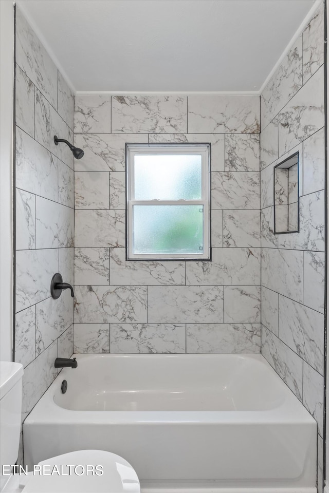 bathroom featuring tiled shower / bath combo and toilet