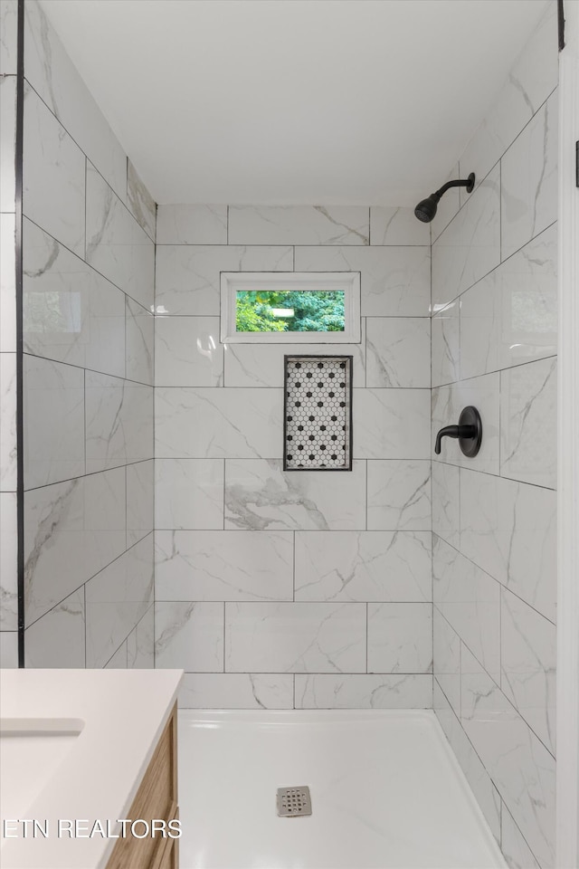 bathroom featuring tiled shower and vanity