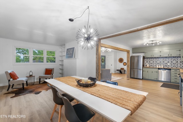 dining space with light hardwood / wood-style floors and a notable chandelier