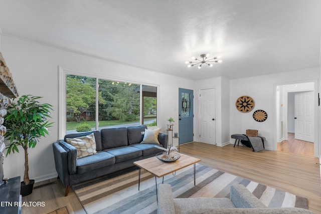 living room with a chandelier, light wood-type flooring, and plenty of natural light