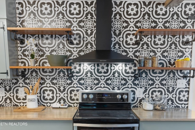 interior space with stainless steel electric range oven and wall chimney exhaust hood