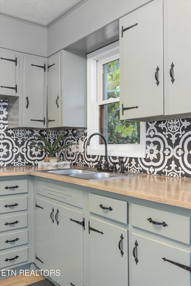 kitchen featuring stainless steel counters, white cabinetry, tasteful backsplash, a textured ceiling, and sink