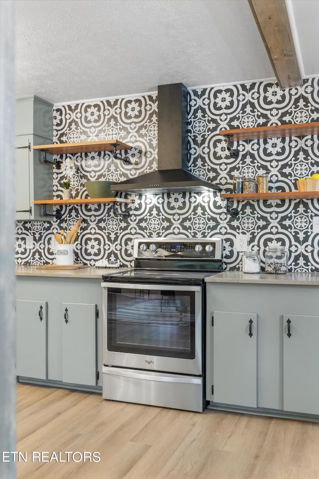 kitchen featuring stainless steel electric range oven, a textured ceiling, light wood-type flooring, and wall chimney exhaust hood