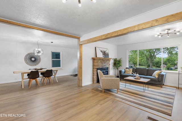 living room featuring light hardwood / wood-style flooring, an inviting chandelier, and a textured ceiling