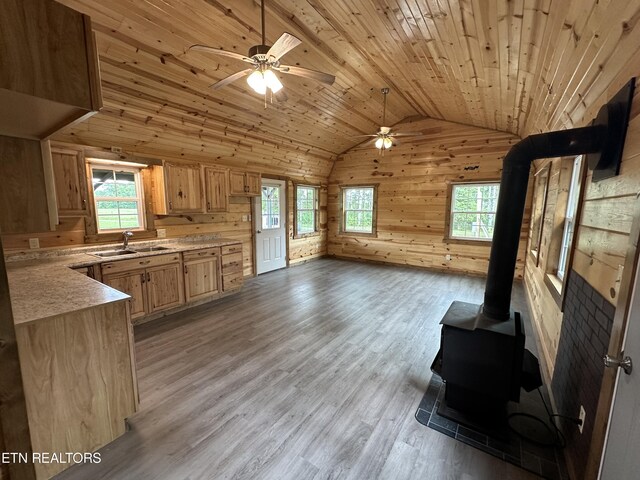 kitchen with light hardwood / wood-style floors, a wood stove, ceiling fan, and wood ceiling