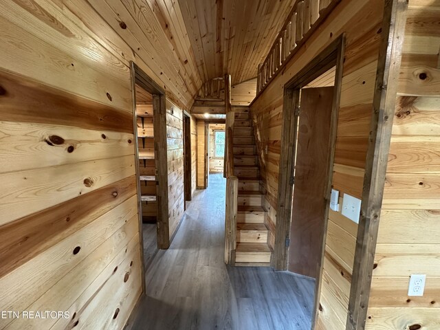 hall featuring wood ceiling, wood walls, hardwood / wood-style flooring, and lofted ceiling