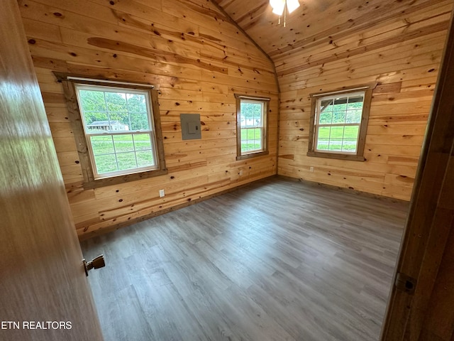 empty room with hardwood / wood-style flooring, lofted ceiling, wood walls, and a wealth of natural light