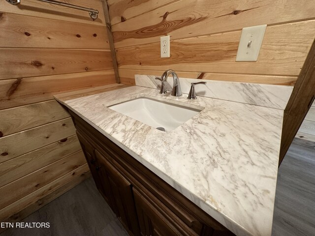 bathroom with vanity, wood walls, and hardwood / wood-style flooring