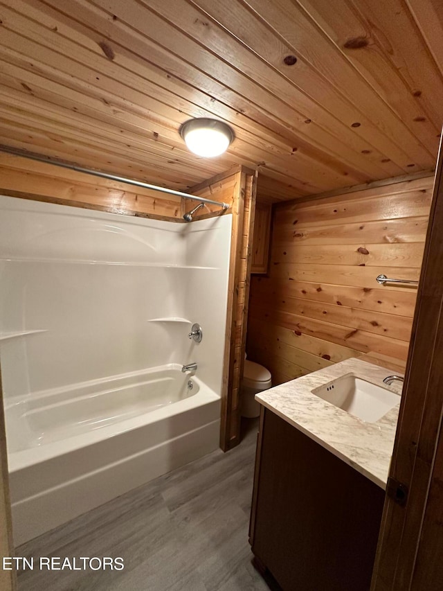 full bathroom featuring vanity, wood-type flooring, washtub / shower combination, wood walls, and toilet