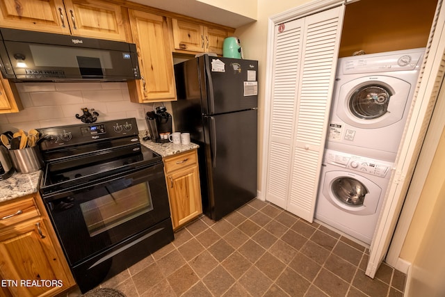 kitchen with stacked washer / dryer, black appliances, light stone countertops, dark tile patterned flooring, and decorative backsplash