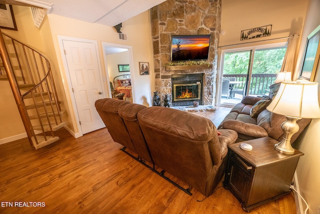 living room with a stone fireplace and hardwood / wood-style floors