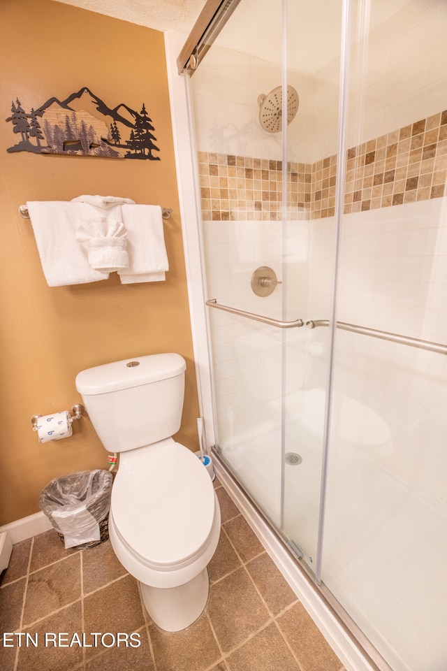 bathroom with tile patterned flooring, a shower with shower door, and toilet