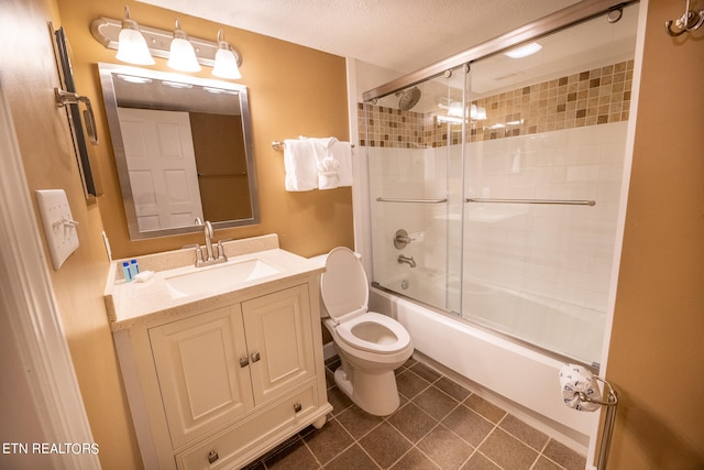 full bathroom with a textured ceiling, toilet, vanity, combined bath / shower with glass door, and tile patterned floors