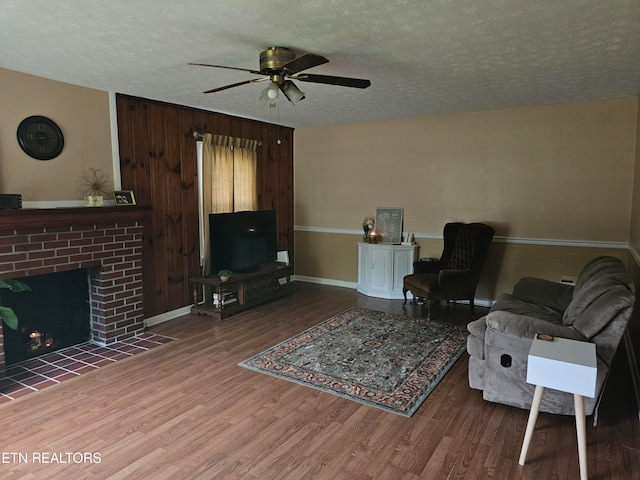 living room featuring a textured ceiling, a brick fireplace, ceiling fan, and hardwood / wood-style floors