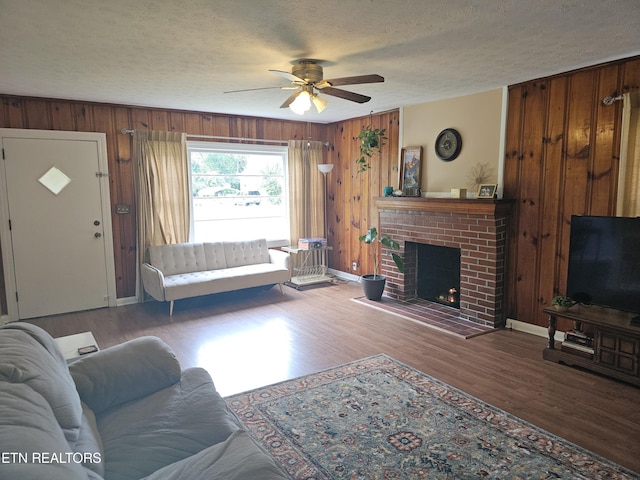 living room featuring wood-type flooring, a textured ceiling, a fireplace, and wood walls