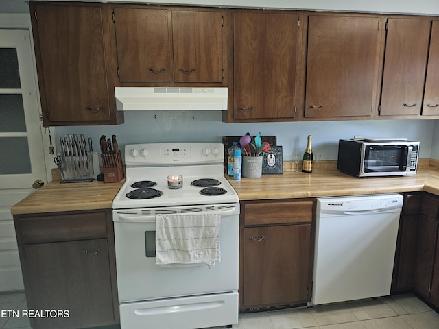 kitchen featuring light tile patterned flooring, dark brown cabinets, and white appliances