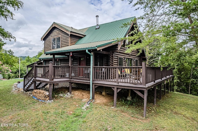 back of property featuring a deck, metal roof, and a lawn