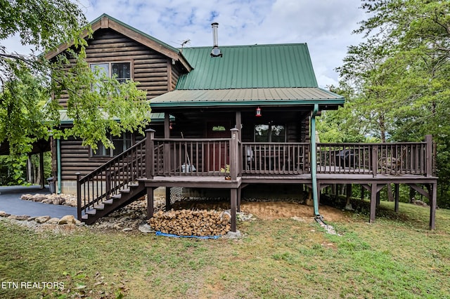 view of front of property featuring a deck, stairs, log siding, and metal roof