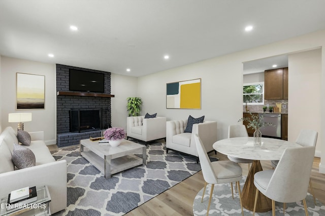 living room with light hardwood / wood-style floors and a brick fireplace