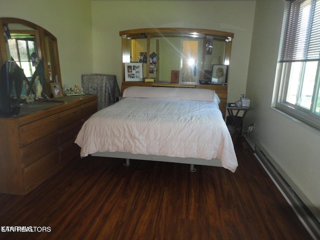 bedroom with a baseboard heating unit and hardwood / wood-style floors