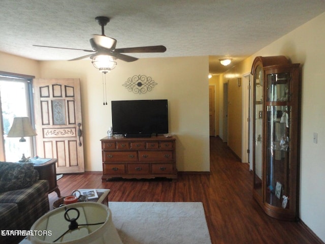 living room with ceiling fan, a textured ceiling, and dark hardwood / wood-style flooring