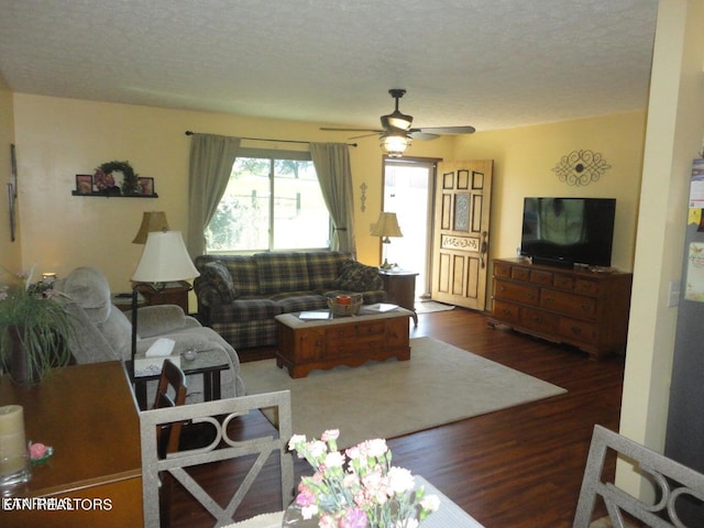 living room featuring ceiling fan, dark wood-type flooring, and a textured ceiling