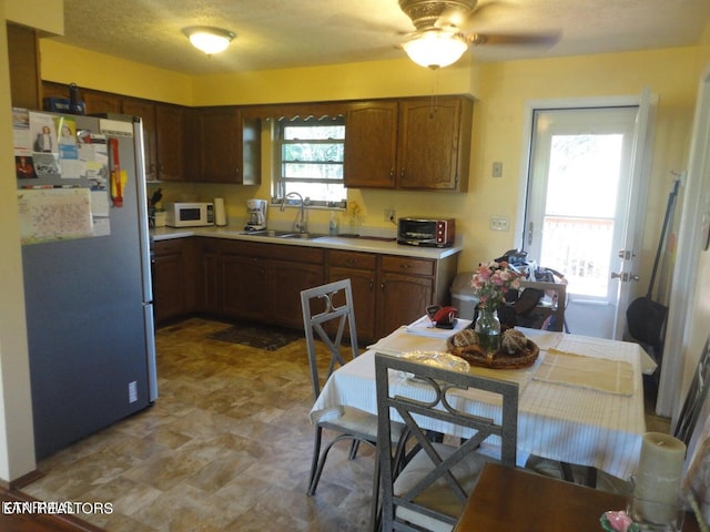 kitchen with sink, stainless steel refrigerator, light tile patterned floors, and ceiling fan