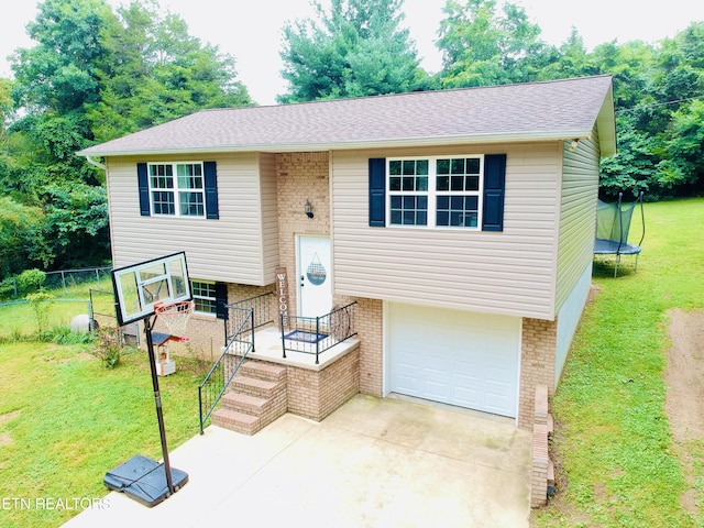 bi-level home featuring a garage, a front yard, and a trampoline