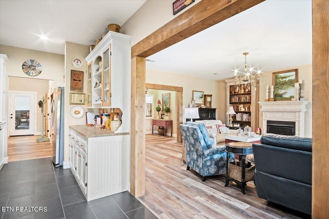 living room with a notable chandelier, a wealth of natural light, dark hardwood / wood-style floors, and beamed ceiling