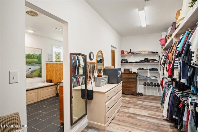 walk in closet with light hardwood / wood-style flooring