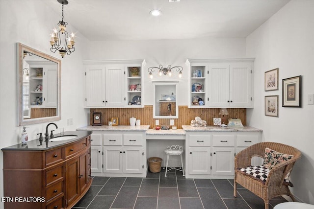 kitchen with sink, decorative light fixtures, dark tile patterned floors, and white cabinets