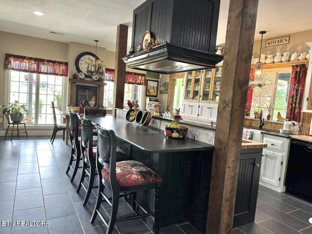 kitchen featuring hanging light fixtures, a breakfast bar, custom range hood, and dark tile patterned floors