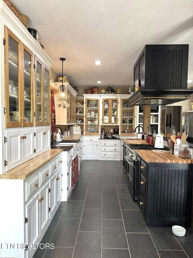 kitchen featuring pendant lighting, white cabinetry, a textured ceiling, wood counters, and dark tile patterned flooring