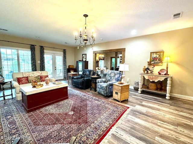 living room with hardwood / wood-style flooring, a textured ceiling, a chandelier, and french doors