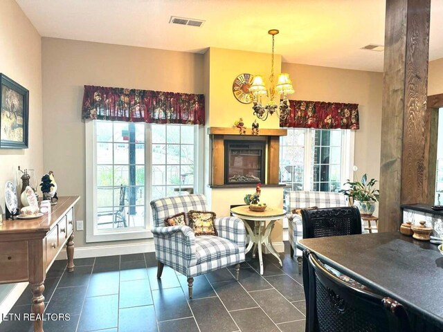 sitting room with plenty of natural light, dark tile patterned floors, and a notable chandelier