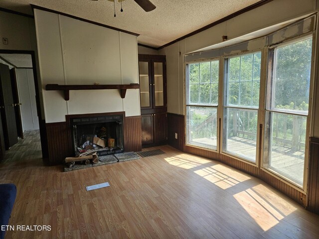 unfurnished living room featuring a wainscoted wall, wood finished floors, lofted ceiling, and a textured ceiling