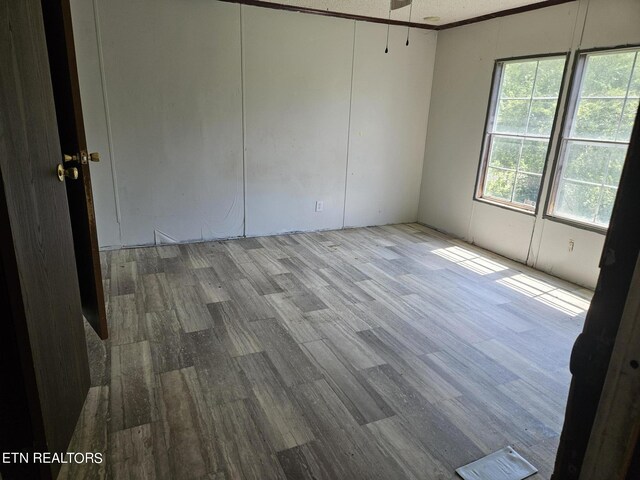 unfurnished room with a ceiling fan, ornamental molding, and wood finished floors