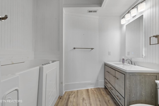 bathroom with hardwood / wood-style flooring, vanity, and a bath