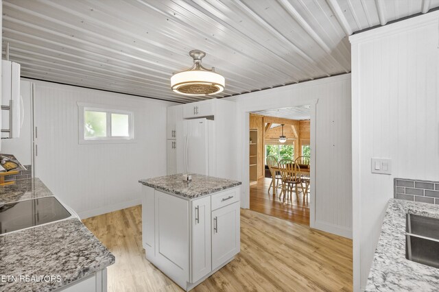 kitchen with white fridge, white cabinets, light stone counters, and light hardwood / wood-style floors