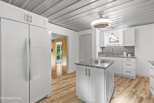 kitchen featuring sink, white cabinetry, a kitchen island, white fridge, and pendant lighting