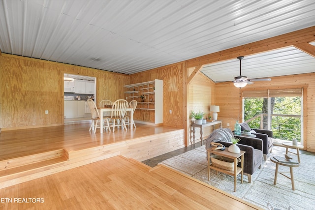 living room with hardwood / wood-style floors, ceiling fan, and wood walls