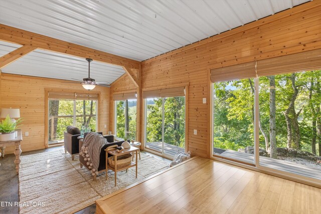 unfurnished living room with hardwood / wood-style flooring, ceiling fan, and wood walls