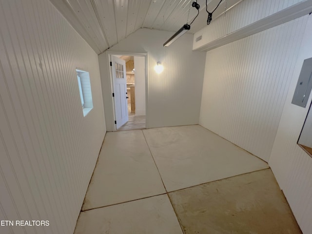 hall with vaulted ceiling, electric panel, and concrete flooring