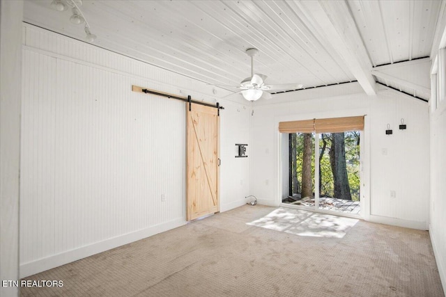 unfurnished room featuring a ceiling fan, a barn door, carpet, and baseboards