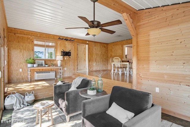 living area with a wall mounted air conditioner, wood walls, and ceiling fan