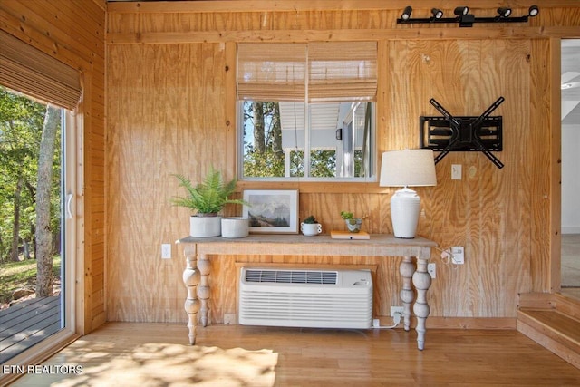 interior space with wood finished floors, wood walls, and a wall unit AC